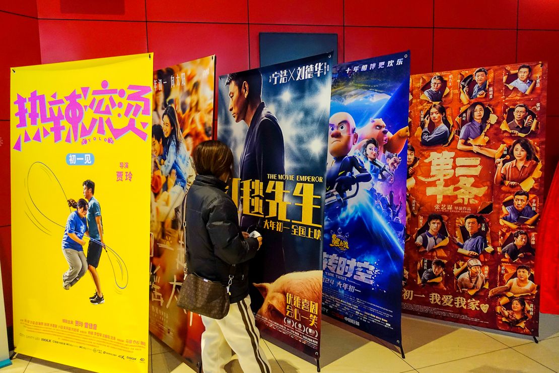 Movie fans walk in front of movie posters at a movie theater in Shanghai, China, on February 10, 2024.