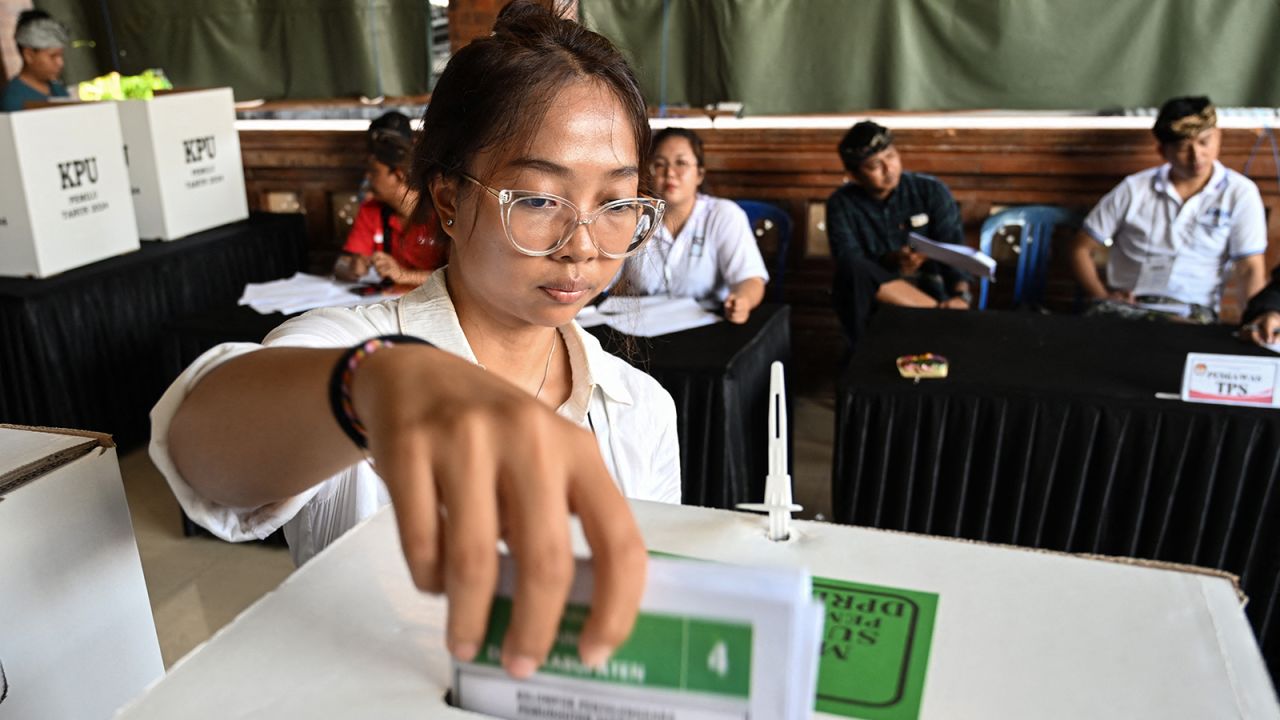 A woman casts her ballot to vote in Indonesia's presidential and legislative elections at a polling station in Banjar Teba, Jimbaran on the resort island of Bali on February 14, 2024.