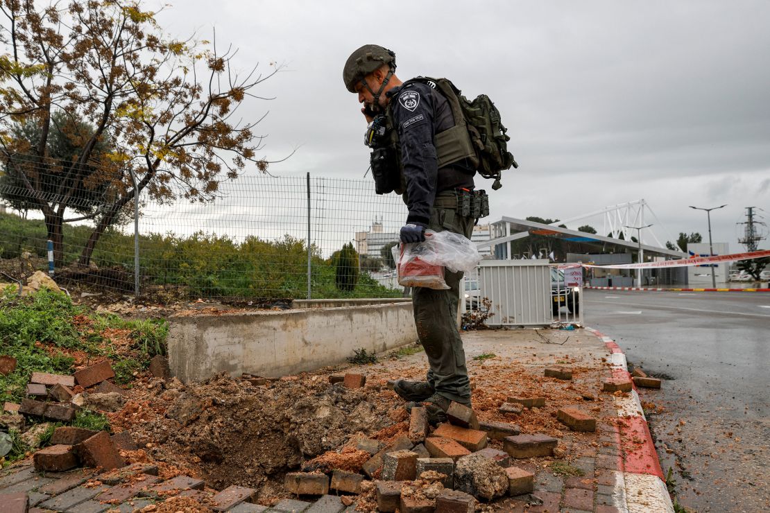 An Israeli policeman inspects the impact crater left by a rocket fired from southern Lebanon where it landed near the entrance of Ziv hospital in Israel's northern city of Safed on February 14, 2024.