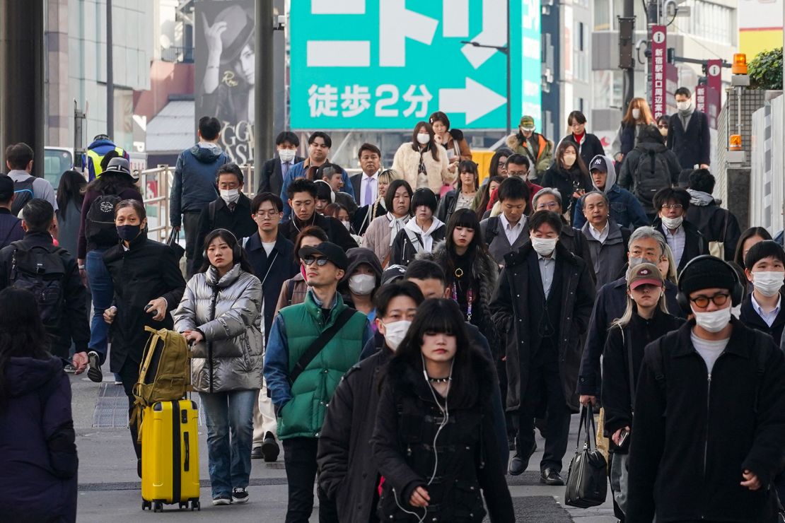 People commuting to work in the morning walk down a street in Tokyo on February 15, 2024.