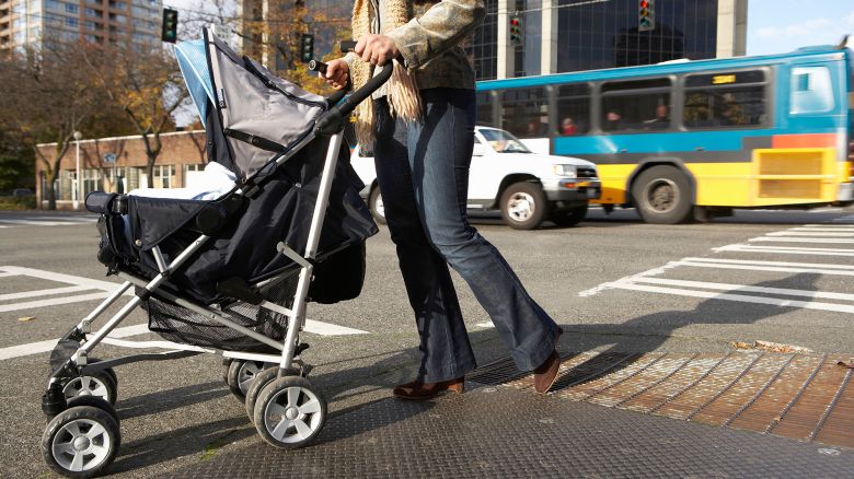 A woman pushes a baby stroller on a sidewalk in Seattle, Washington.