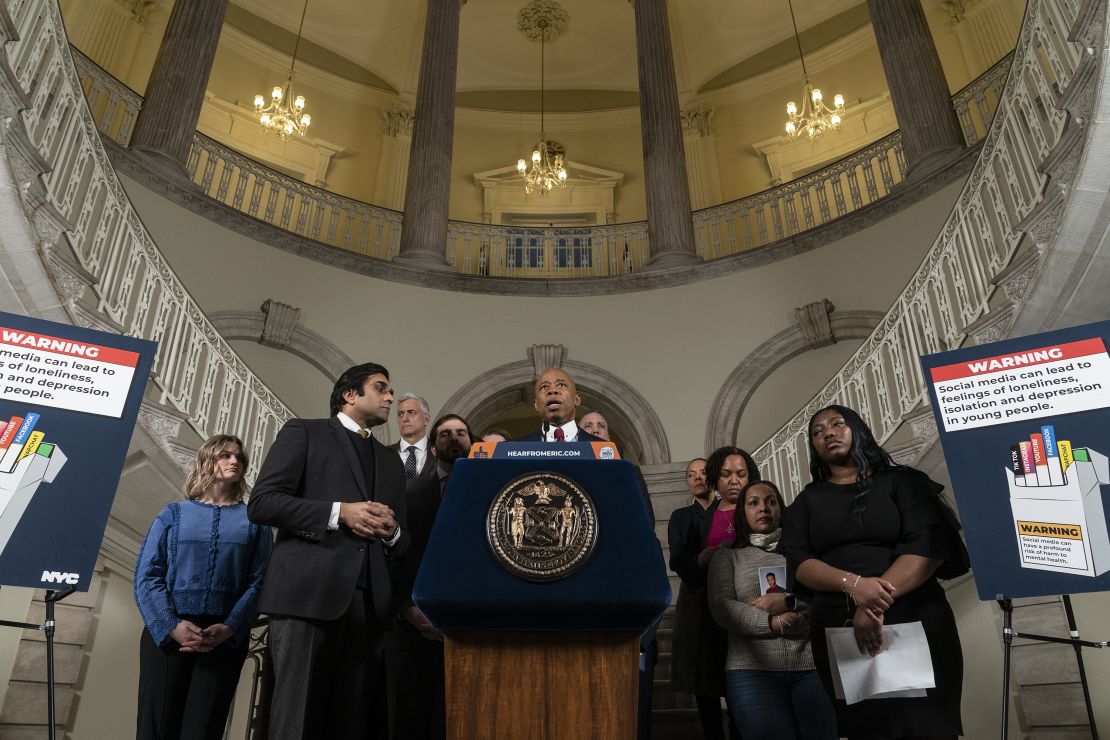 Mayor Eric Adams makes announcement on lawsuit against social media companies at City Hall in New York City. Norma Nazario, whose 15-year-old son Zackery died last year in a New York subway surfing accident after he found videos of the trend on social media, stands by his side, holding a picture of her son.