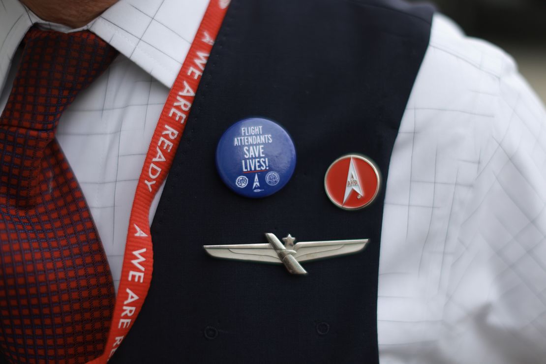 A flight attendant wears a pin reading,' Flight Attendants Save Live!' while picketing Tuesday.