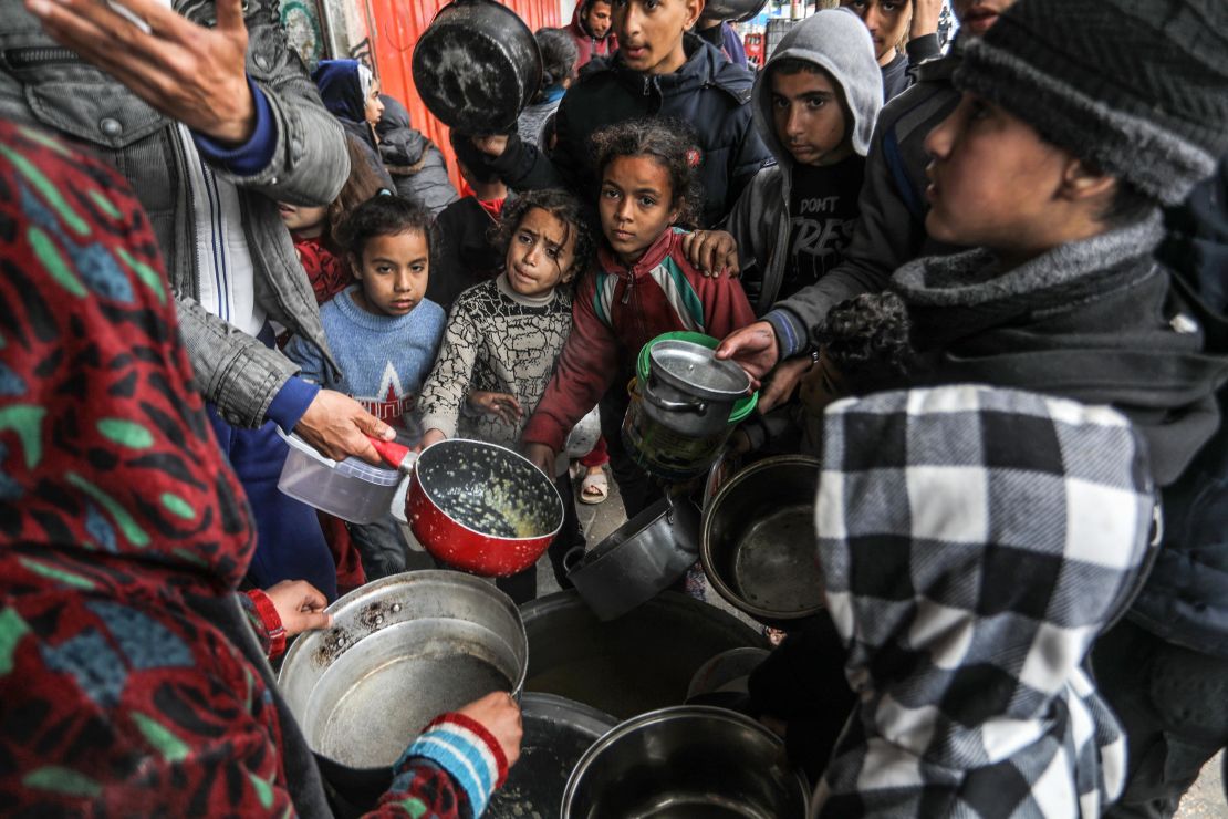 Palestinians holding empty bowls receive food distributed by volunteers amid a hunger crisis and famine risk due to the Israeli embargo imposed on the territory, in Rafah, the southern Gaza Strip on February 18.