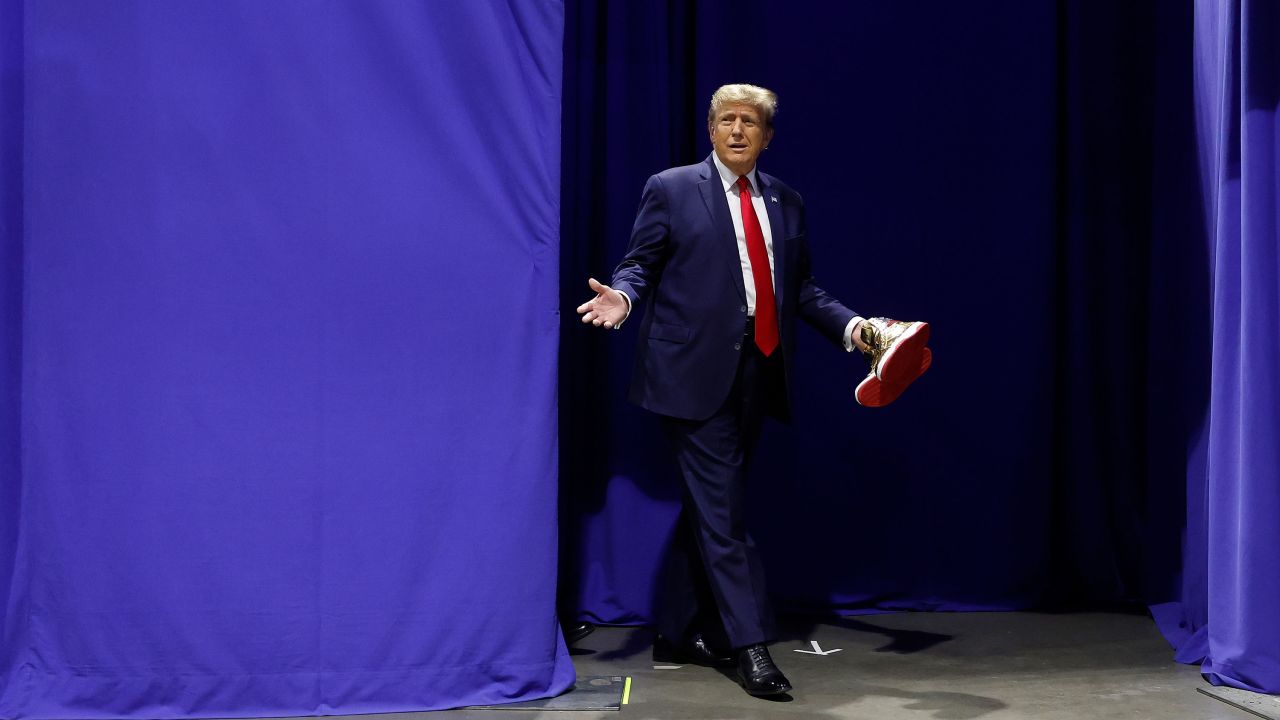 PHILADELPHIA, PENNSYLVANIA - FEBRUARY 17: Republican presidential candidate and former President Donald Trump carries a pair of his new signature shoes before taking the stage at Sneaker Con at the Philadelphia Convention Center on February 17, 2024 in Philadelphia, Pennsylvania. Sneaker Con was founded in 2009 and is one of the oldest events celebrating sneakers, streetwear and urban culture. Trump addressed the event one day after a judge ordered the former president to pay $354 million in his New York civil fraud trial. (Photo by Chip Somodevilla/Getty Images)
