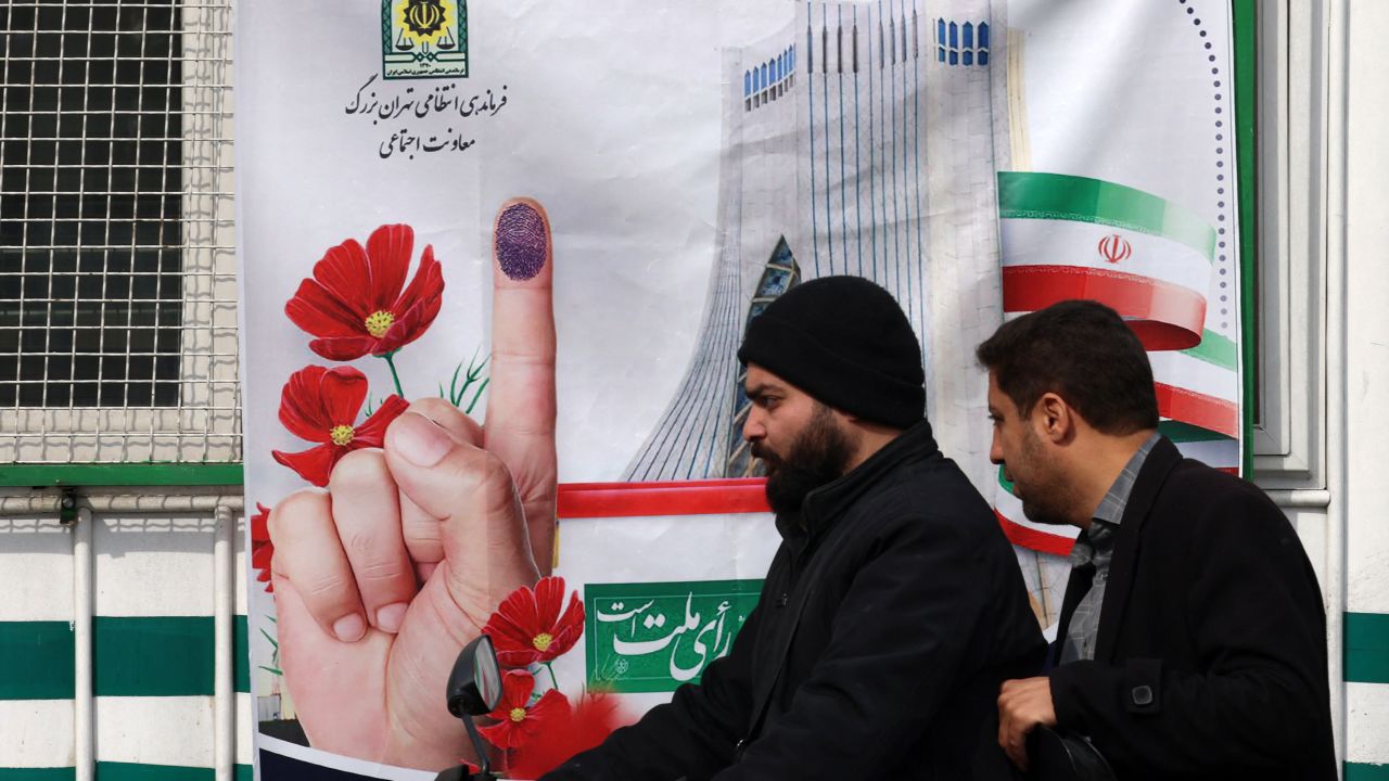 Men ride their scooter in front of a poster encouraging Iranians to vote in the upcoming elections, in Tehran on February 24, 2024. Voters are due to cast their ballots on March 1 to pick new members of Iran's parliament, as well as the Assembly of Experts, a key body in charge of appointing the country's supreme leader. (Photo by ATTA KENARE / AFP) (Photo by ATTA KENARE/AFP via Getty Images)