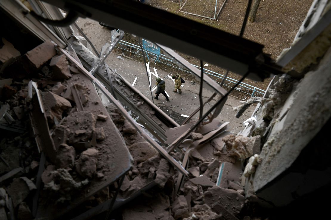 Law enforcement officers walk past a building damaged as a result of shelling in Donetsk.