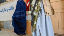 Taliban security personnel stands guard as an Afghan burqa-clad woman waits to receive winter kit from UNICEF at Fayzabad in Badakhshan province on February 25, 2024. (Photo by Wakil Kohsar / AFP) (Photo by WAKIL KOHSAR/AFP via Getty Images)