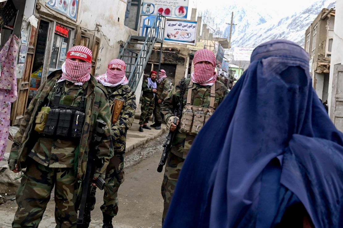 Taliban security personnel stand guard as a burqa-clad woman walks through a market in Baharak district of Badakhshan province, Afghanistan on February 26, 2024.