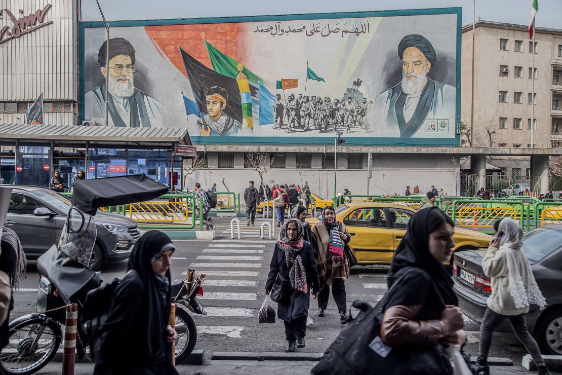 Pedestrians pass by a poster featuring Ayatollah Khomeini, the first Supreme Leader of the Islamic Republic (right) and Ayatollah Khamenei, the current Supreme Leader (left) on February 24 in Tehran, Iran.