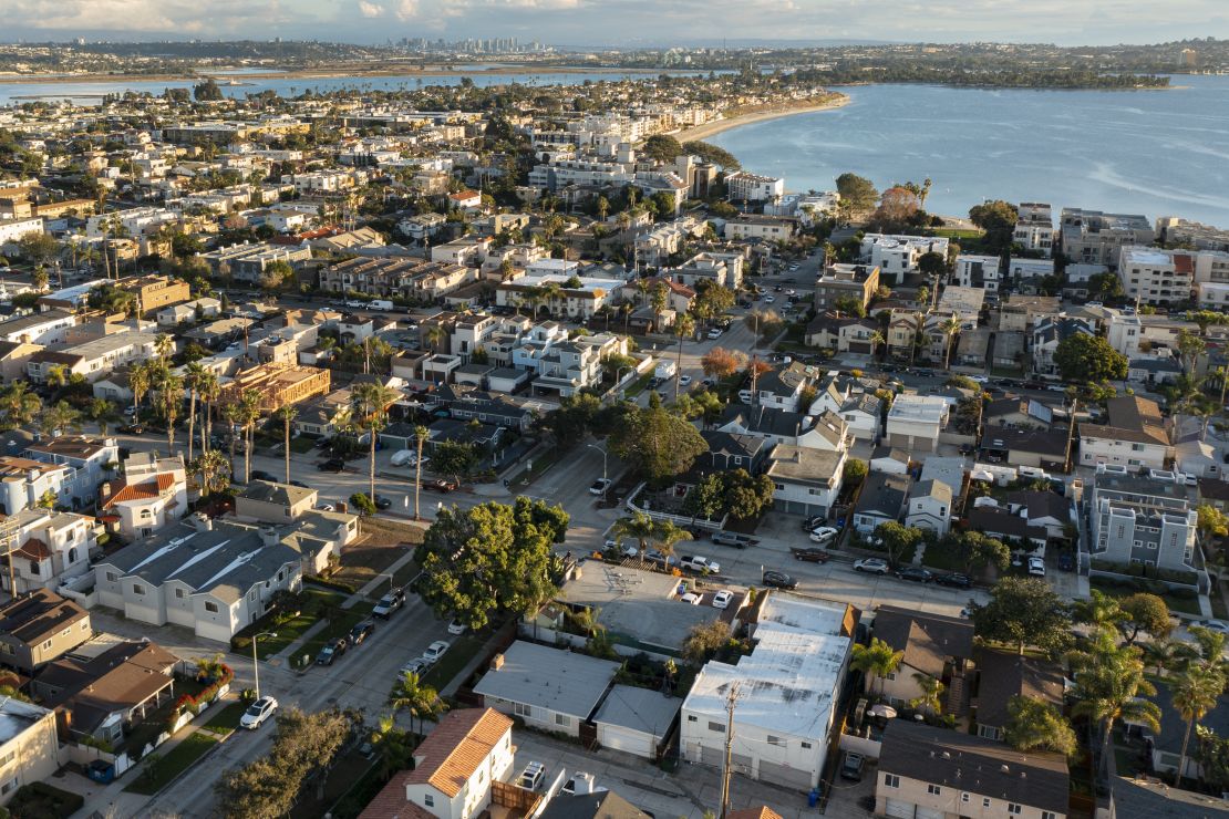 In an aerial view, condominiums, apartments and single family homes line the streets of Pacific Beach near Sail Bay in Mission Bay as the sun sets on December 22, 2023 in San Diego, California.