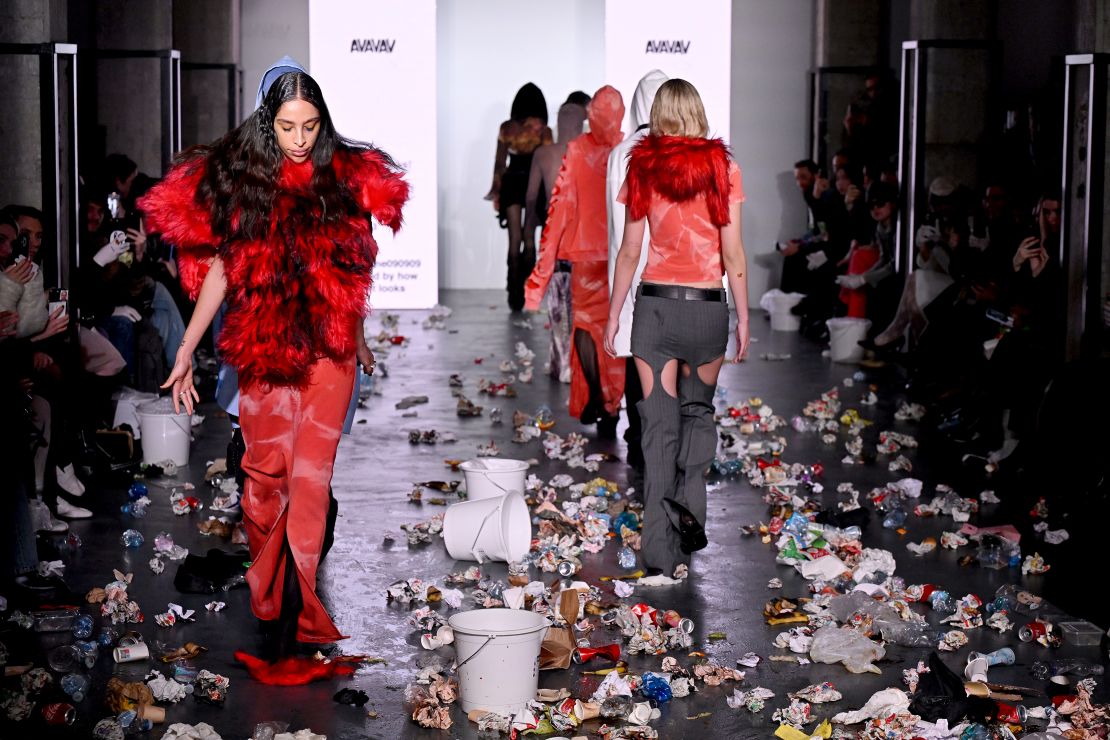 Models walk a trash-strewn runway at the Avavav fashion show, while big screens at either side flashed up excerpts from previous bad show reviews.