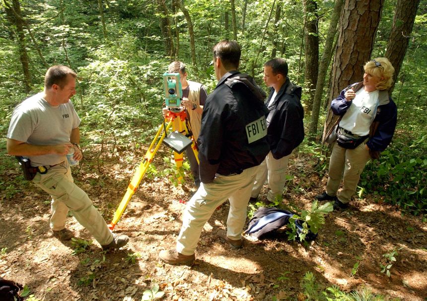 An FBI evidence team surveys a campsite used by serial bomber Eric Robert Rudolph on June 2, 2003 in the woods outside Murphy, North Carolina.