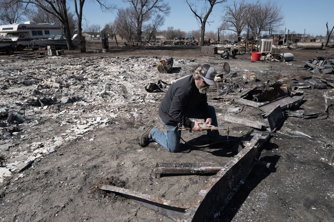 A homeowner cuts up the frame of his doublewide mobile after it was destroyed by the Smokehouse Creek Fire in Stinnett, Texas.