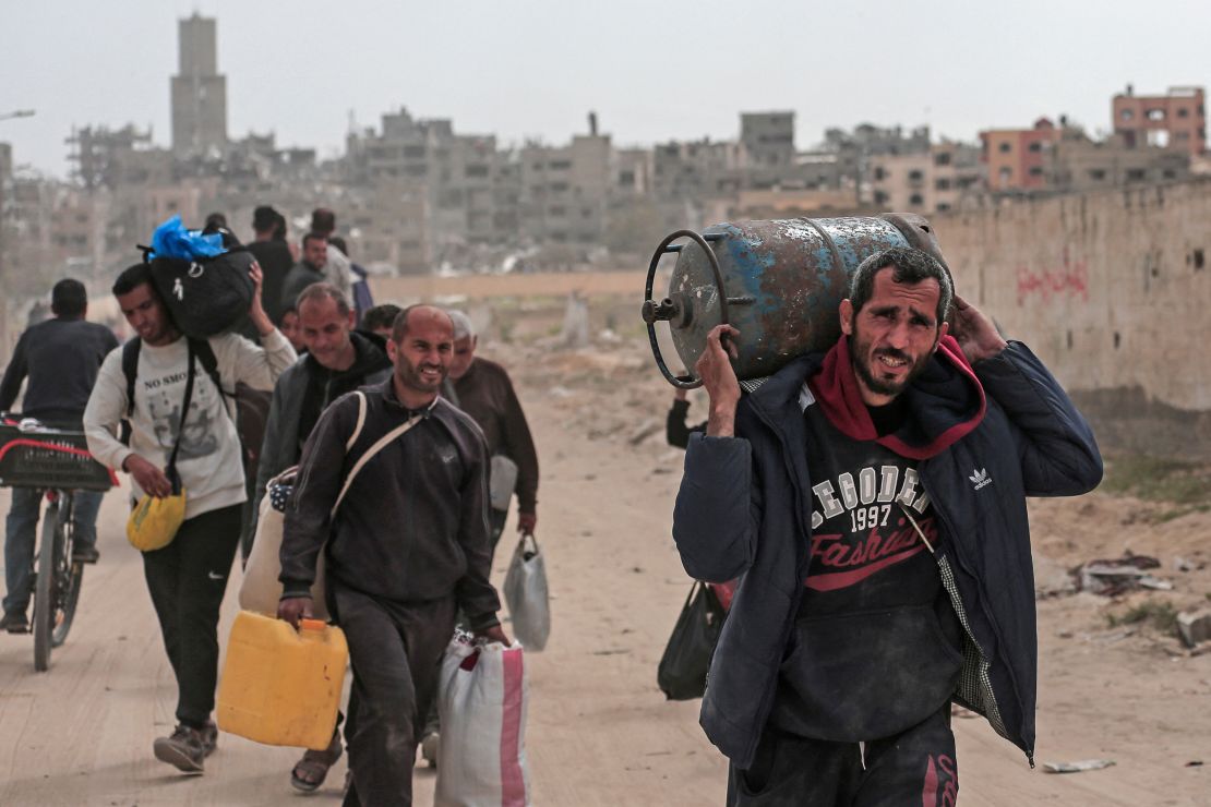 Displaced Palestinians carry their belongings through a street in Khan Yunis in the southern Gaza Strip on March 6, 2024, amid the ongoing conflict between Israel and the Hamas movement.