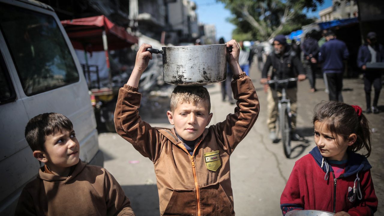 TOPSHOT - Children carry kitchen utensils as they walk toward a food distribution point in Khan Yunis in the southern Gaza Strip on March 7, 2024, amid ongoing battles between Israel and the Palestinian militant group Hamas. (Photo by AFP) (Photo by -/AFP via Getty Images)