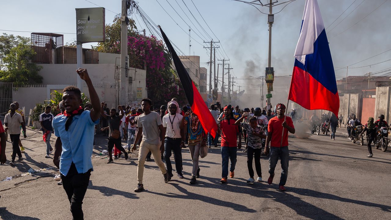 People, carrying Haitian flags, march during a demonstration demanding the resignation of Haitian Prime Minister Ariel Henry in Haiti on March 7, 2024.