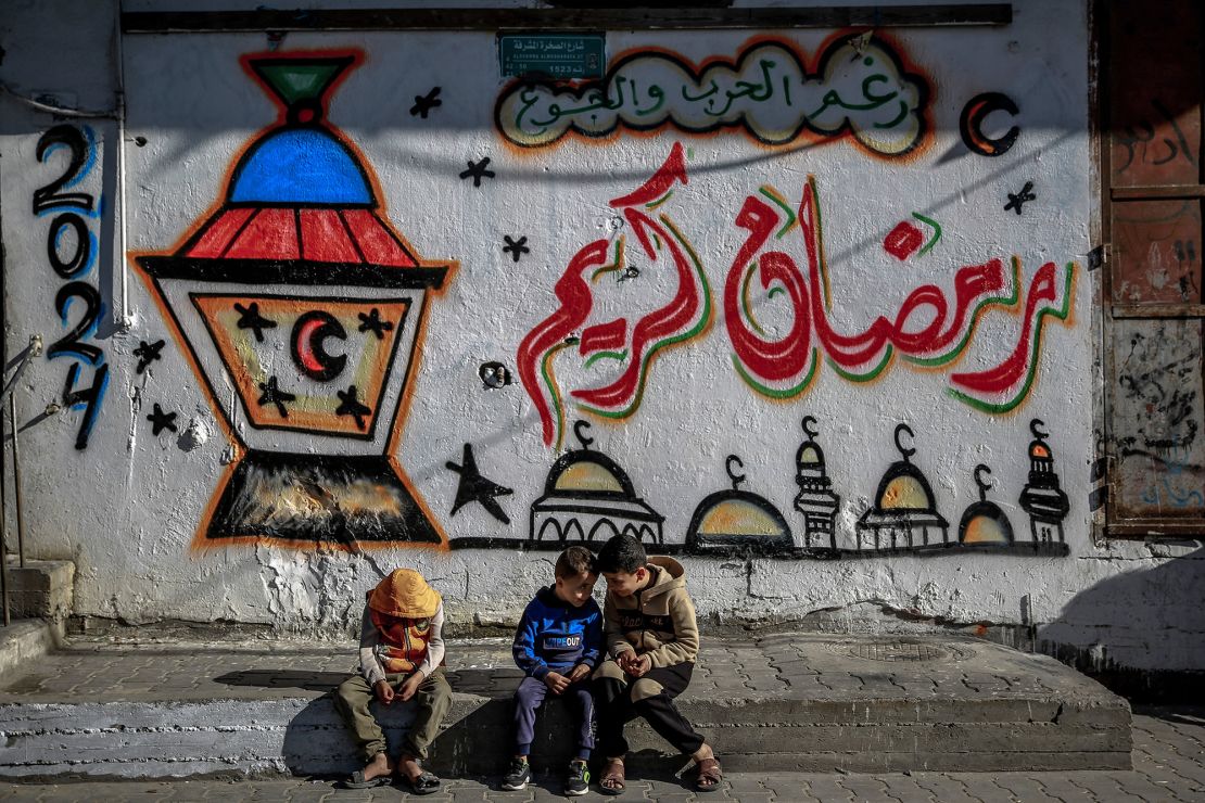 Palestinian children sit in front of Ramadan-themed mural in Gaza City on March 8.