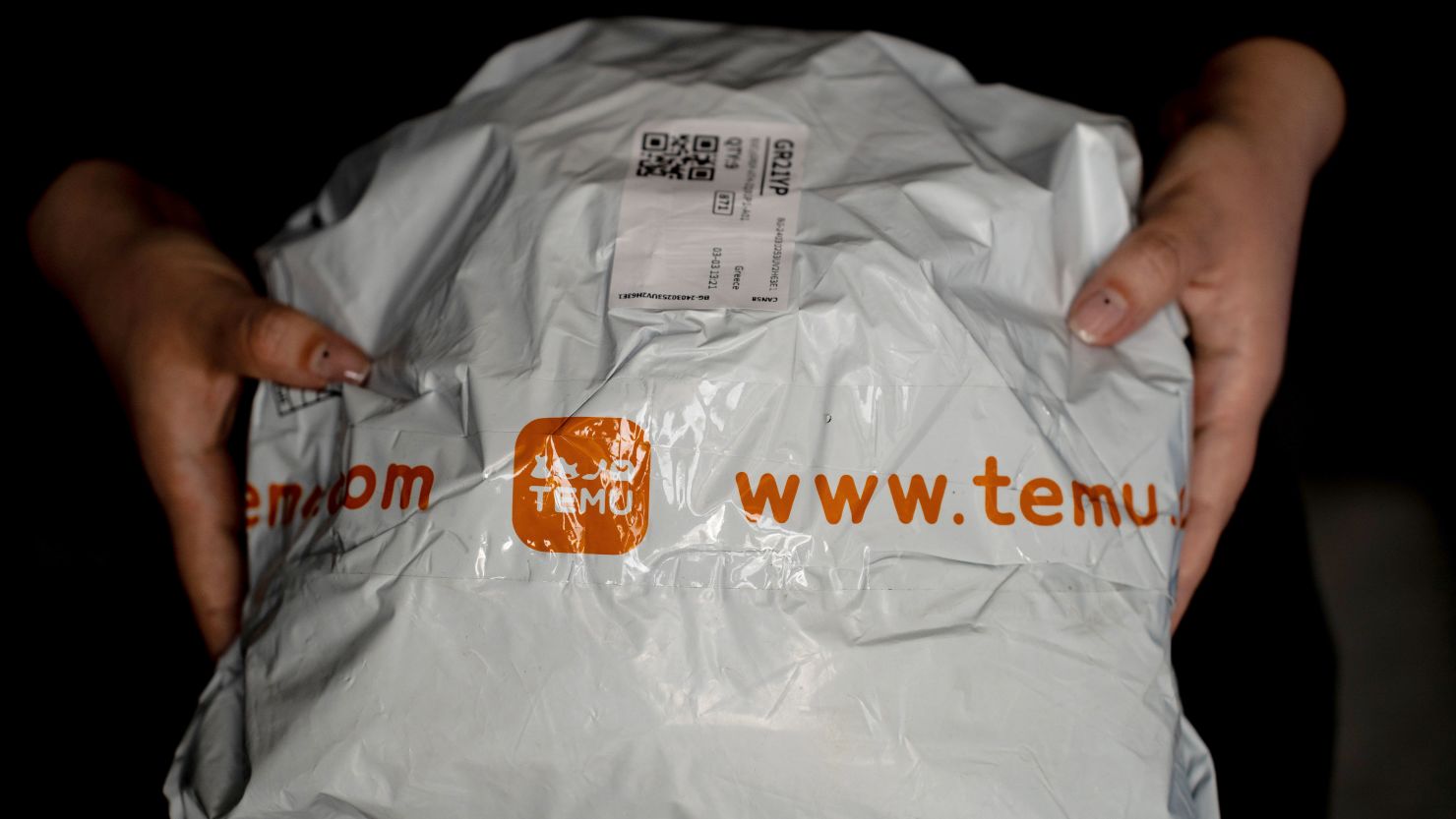 A person holds a package from Temu.
