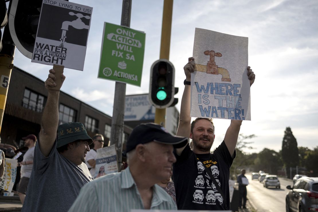 Residents hold placards during a protest against water shortages in the Blairgowrie area of Johannesburg on March 12, 2024.