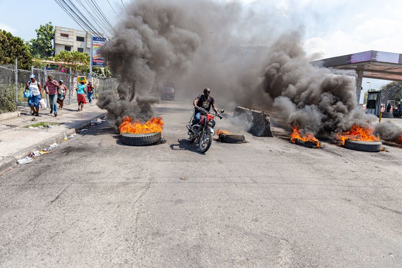 PORT-AU-PRINCE, HAITI- MARCH 12: 
A motorcyclist passes burning tires during a demonstration against CARICOM for the decision following the resignation of Haitian Prime Minister Ariel Henry as representatives of the Caribbean Community (CARICOM) and Haitian actors made an agreement for political transition in Haiti it a historic decision that was made by the formation of a seven-member Presidential Council (CP), and the Haitian government on Tuesday extended the night-time curfew and state of emergency in the capital of Port-au-Prince for a month amid a wave of violence triggered by armed groups in Port-au-Prince, Haiti, on March 12, 2024. (Photo by Guerinault Louis/Anadolu via Getty Images)