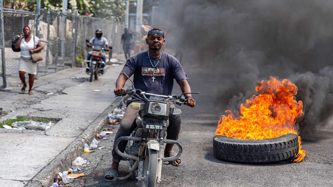 A motorcyclist passes burning tires during a demonstration against CARICOM, in Port-au-Prince, Haiti, on March 12, 2024.