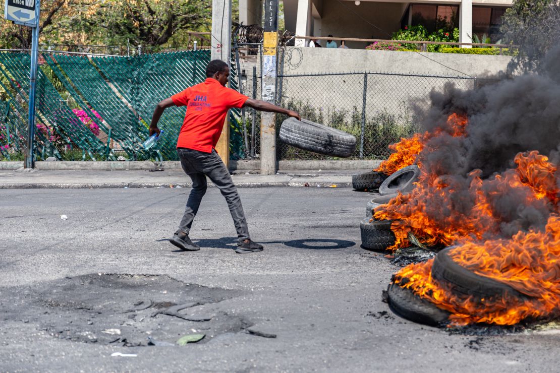 A man sets a tire on fire during a demonstration following the resignation of Haitian Prime Minister Ariel Henry.