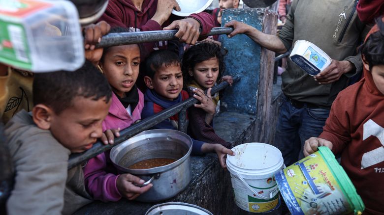 Displaced Palestinians gather to collect food donated by a charitable youth group before breakfast, on the second day of the holy month of Ramadan in Rafah, in the southern Gaza Strip on March 12, 2024.