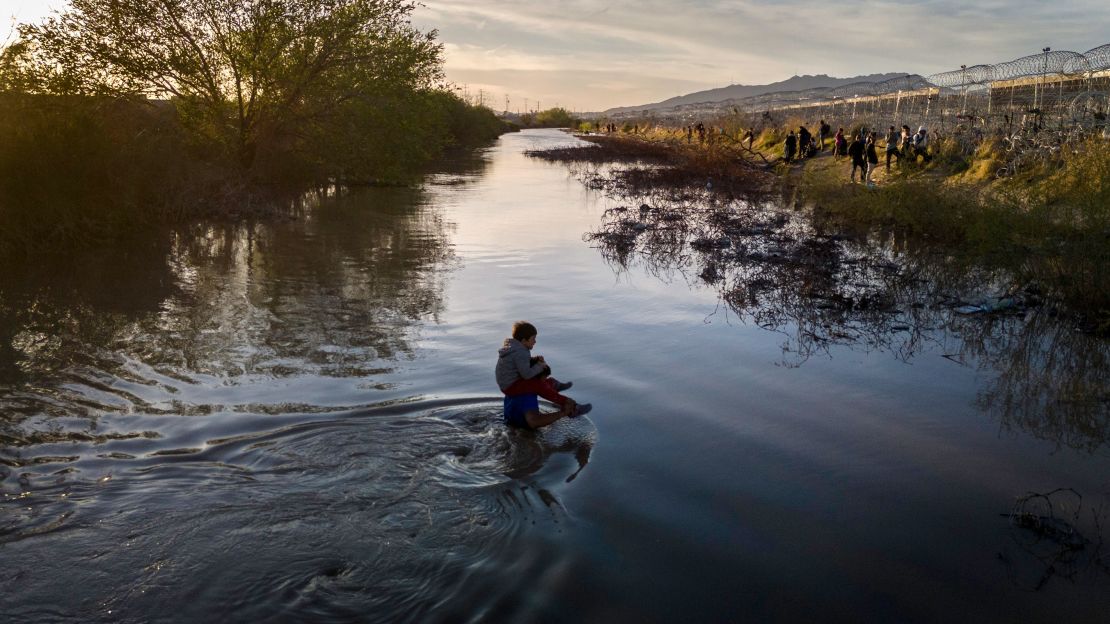 Immigrants wade through the Rio Grande while crossing from Mexico into El Paso, Texas, on March 12, 2024.