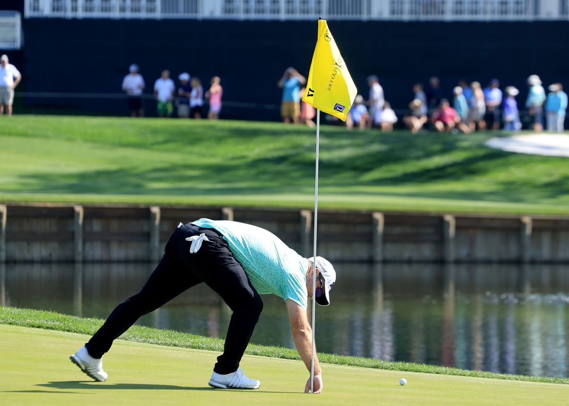 Fox plucks his ball from the cup of the 17th hole.