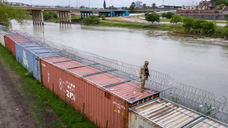 A Texas National Guard soldier stands atop a barrier of shipping containers and razor wire while guarding the US-Mexico border on March 17, in Eagle Pass, Texas. 