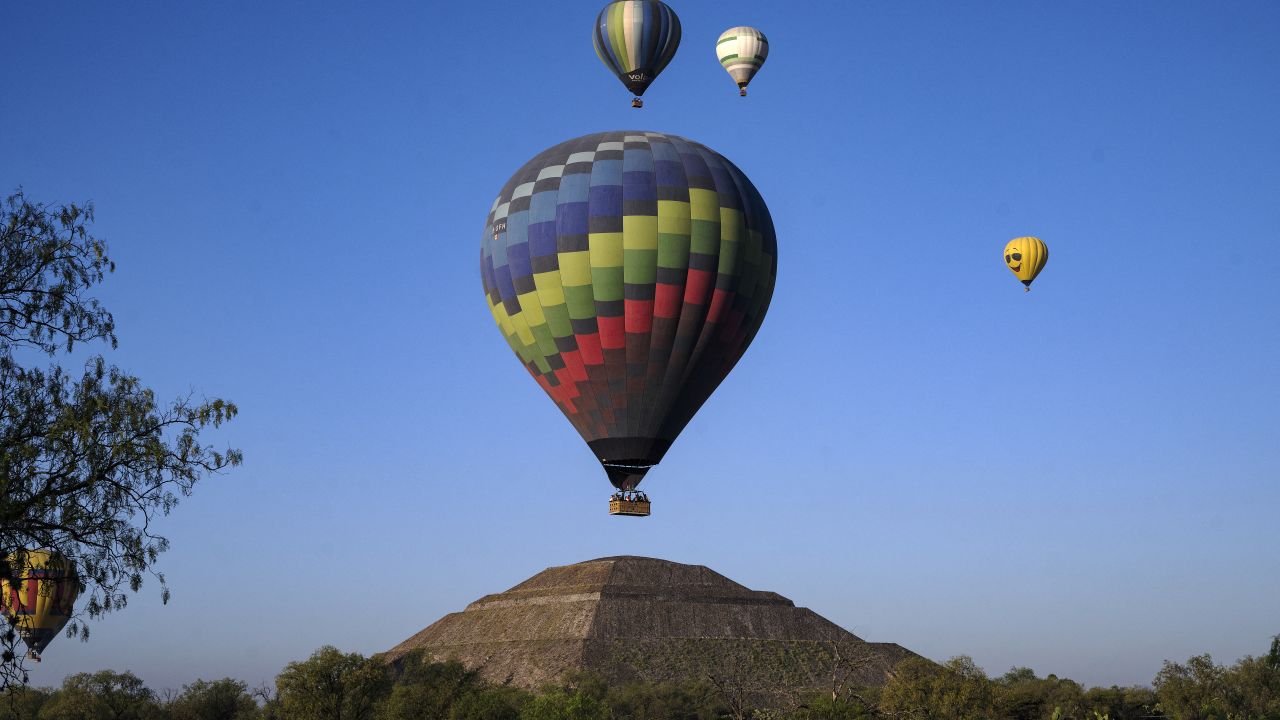 TOPSHOT - Hot air balloons fly over the Teotihuacan pyramids in the San Juan Teotihuacan municipality, Mexico State, during the spring equinox celebration on March 21, 2024. (Photo by CARL DE SOUZA / AFP) (Photo by CARL DE SOUZA/AFP via Getty Images)