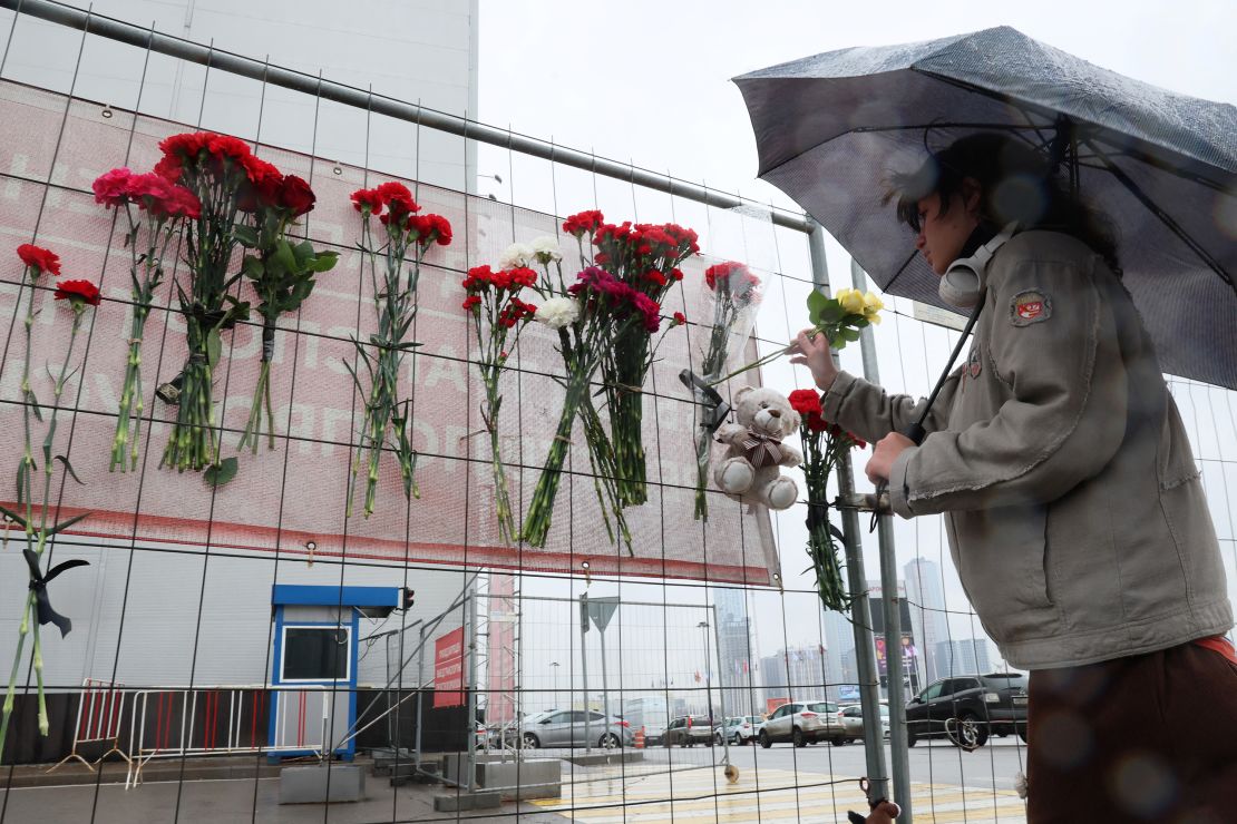 A person places flowers at a makeshift memorial in front of the Crocus City Hall.