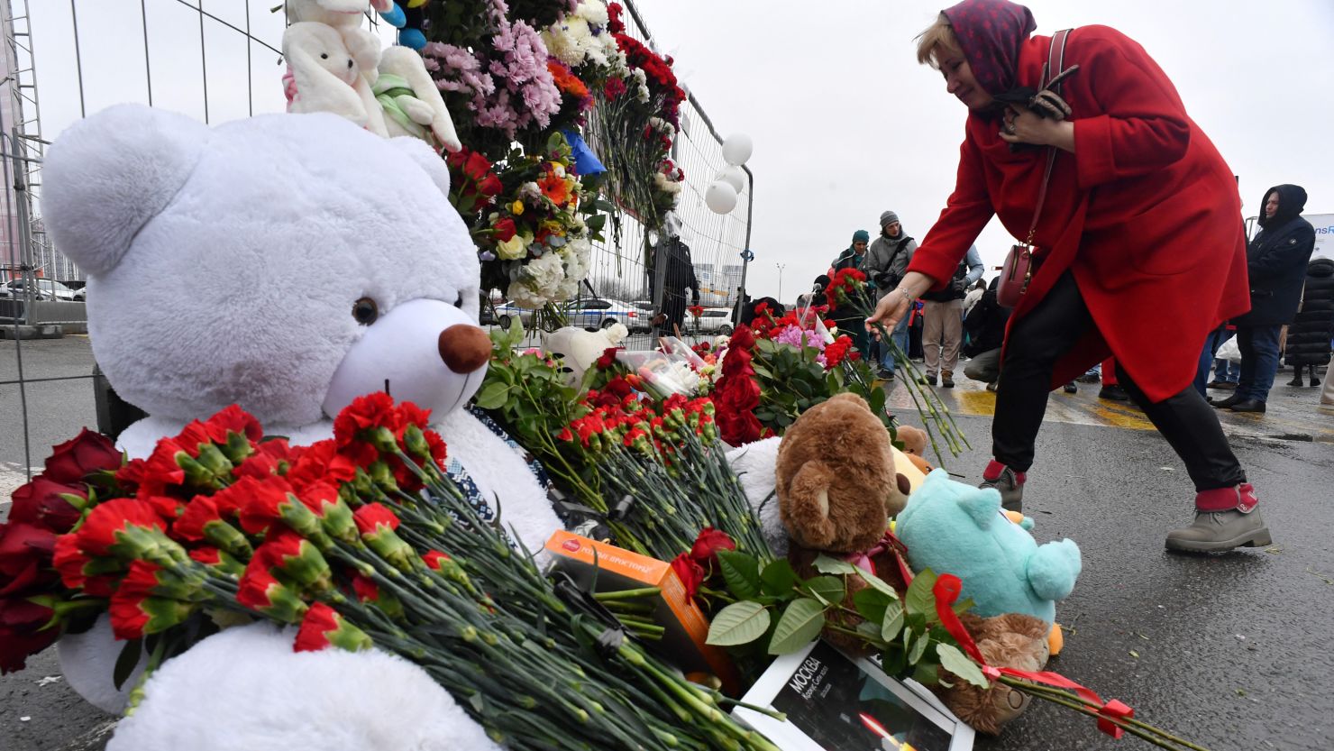 A woman lays flowers at a makeshift memorial in front of the Crocus City Hall, a day after a gun attack in Krasnogorsk, outside Moscow, on March 23, 2024.