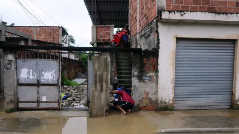 People try to remove water from their flooded house after a rainstorm on the outskirts of Rio de Janeiro on Sunday.