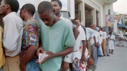 A Haitian man checks his personal documents as he waits in line with dozens of others outside a temporary US refugee office July 11, 1994 in Port-au-Prince. Haitians who apply to US offices in Haiti may be allowed to come to the United States if they are granted refugee status. (Photo by Pedro UGARTE / AFP) (Photo by PEDRO UGARTE/AFP via Getty Images)