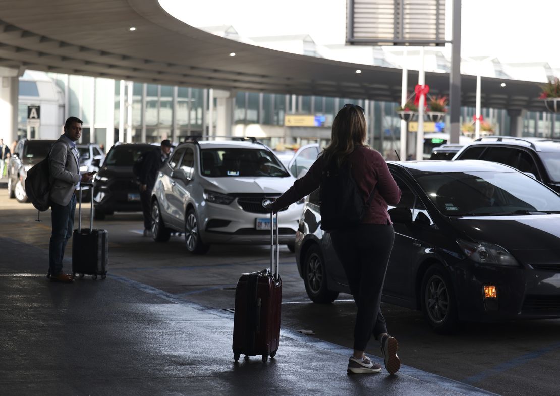 Ride-share passengers wait for their rides outside of Terminal 2 at O'Hare International Airport in Chicago on Dec. 8, 2023.