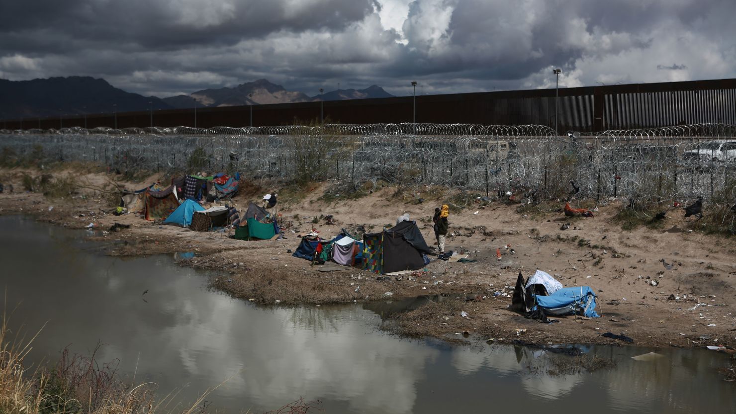 Migrants build makeshift tents with blankets to protect themselves from the cold as an American helicopter guards the border in Ciudad Juarez, Mexico, on March 26, 2024.
