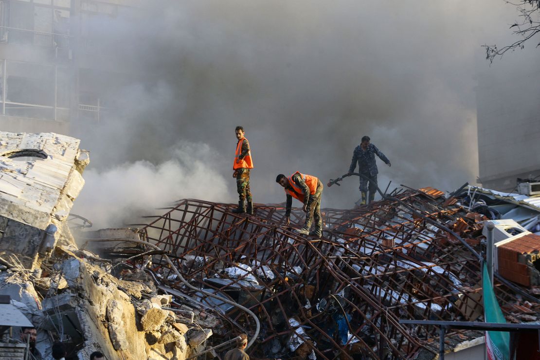 Emergency personnel extinguish a fire at the site of strikes, which hit a building next to the Iranian embassy in Syria's capital Damascus, on April 1, 2024.