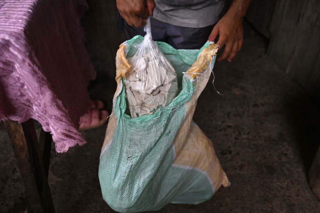 A man shows a bag with coca paste, a raw extract of the coca leaf, in a laboratory in the Micay Canyon, a mountainous area and bastion of the Central General Staff (EMC) in the department of Cauca, southwest Colombia, on March 25, 2024.