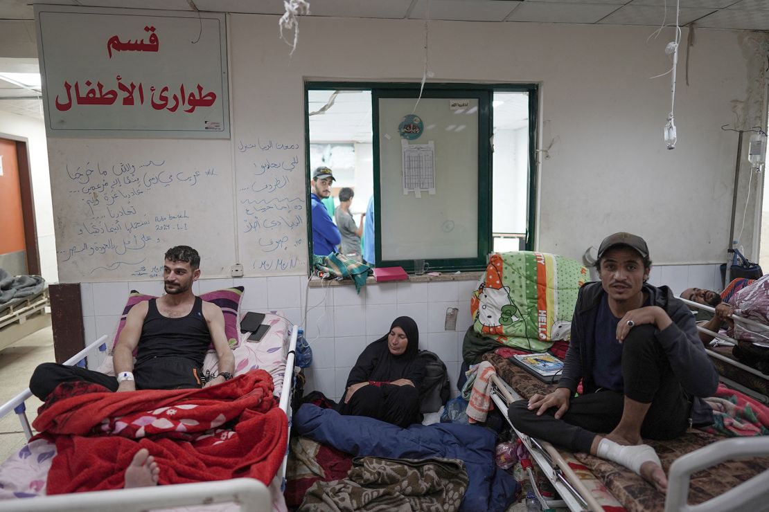 A Palestinian woman sits on the floor between patients at the Al Aqsa Martyrs Hospital in Deir Al-Balah in the central Gaza Strip on April 3.