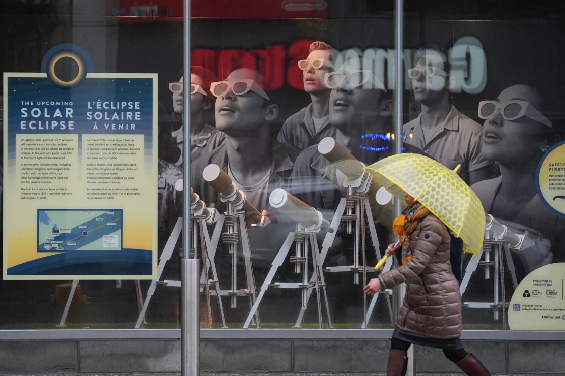 A pedestrian walks past a solar eclipse information board on a rainy day in Toronto on April 3, 2024. Many would-be viewers are worried about bad weather, particularly in points south.