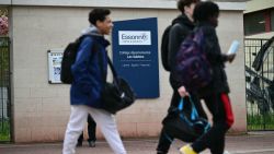 Middle schoolers walk by an indicative panel reading "Departmental middle school - Les Sablons" at the entrance of the school Les Sablons in Viry-Chatillon on April 5, 2024, a day after a teenage boy was assaulted and rushed to the hospital. A 15-year-old teenager has been badly beaten in a town south of Paris and rushed to hospital following a cardiac arrest, in the latest incident of school violence in France, on April 4, 2024. (Photo by Miguel MEDINA / AFP) (Photo by MIGUEL MEDINA/AFP via Getty Images)