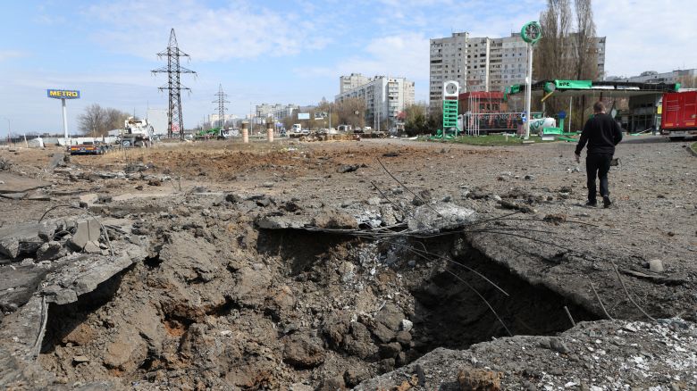 A man walks past a crater after missiles strike in Kharkiv on April 6, 2024, amid Russian invasion in Ukraine.