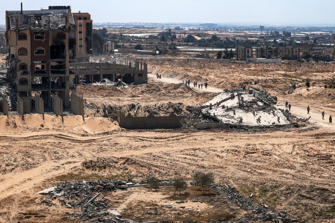 People walk past damaged and destroyed buildings in Khan Yunis on April 7, after Israel pulled its ground forces out of the area.