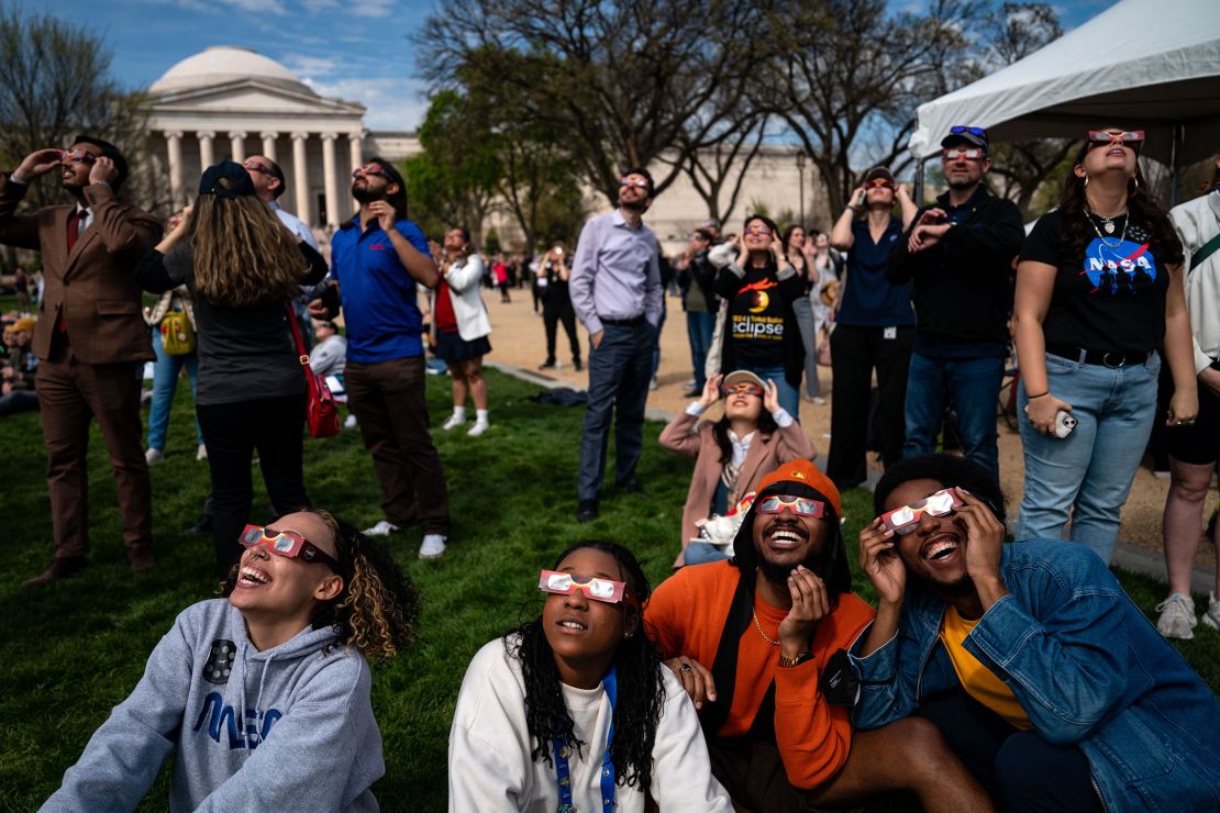 People gather on the National Mall to view the solar eclipse on April 8, 2024, in Washington, DC.