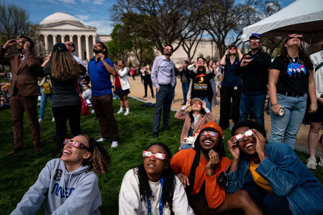 People gather on the National Mall to view the solar eclipse on April 8, 2024, in Washington, DC.