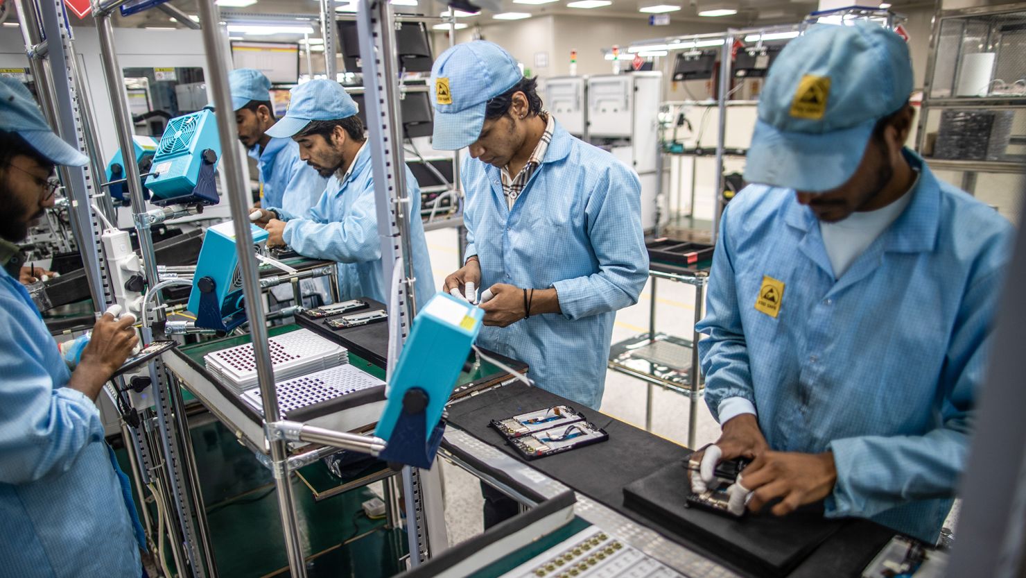Employees work on a mobile phone assembly line at a subsidiary of Dixon Technologies in Noida, India.