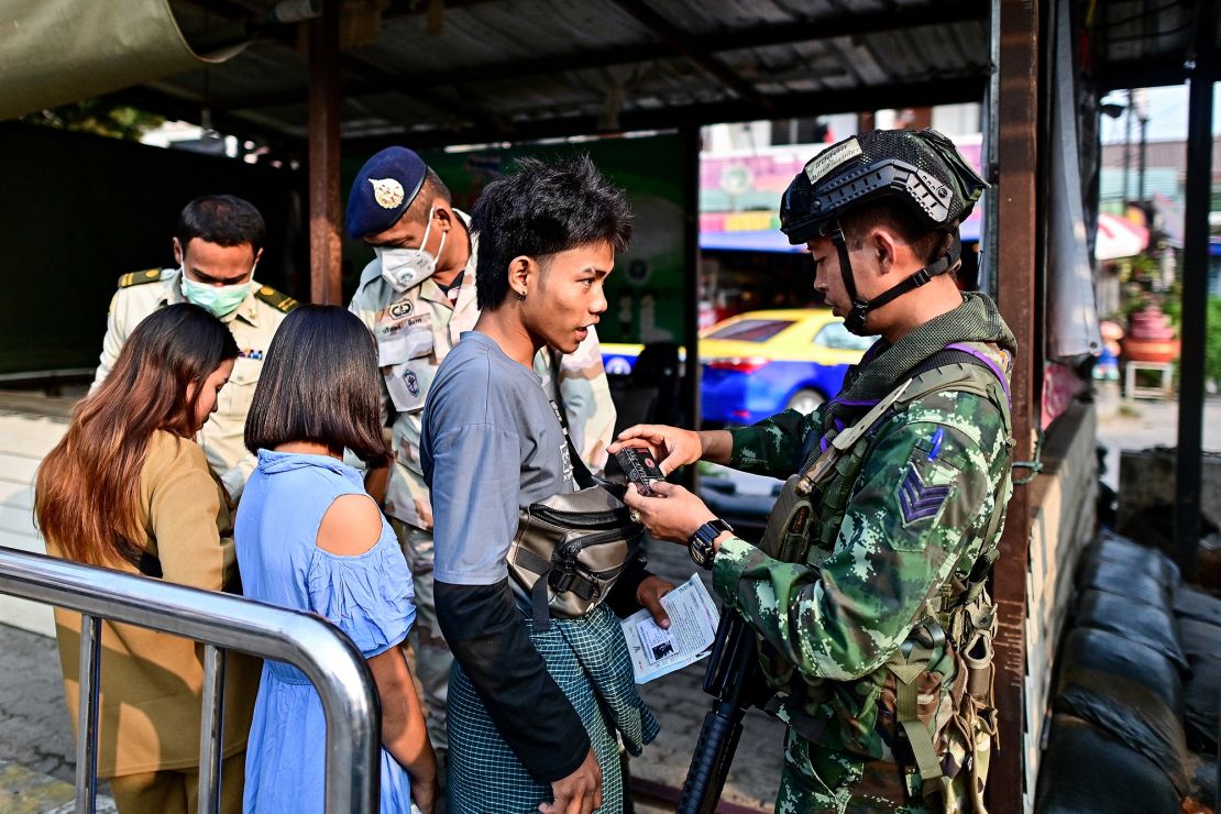 A Thai military personnel (R) checks the bag of a Myanmar national after he cross over into Thailand, at the Tak border checkpoint in Thailand's Mae Sot district on April 11, 2024.