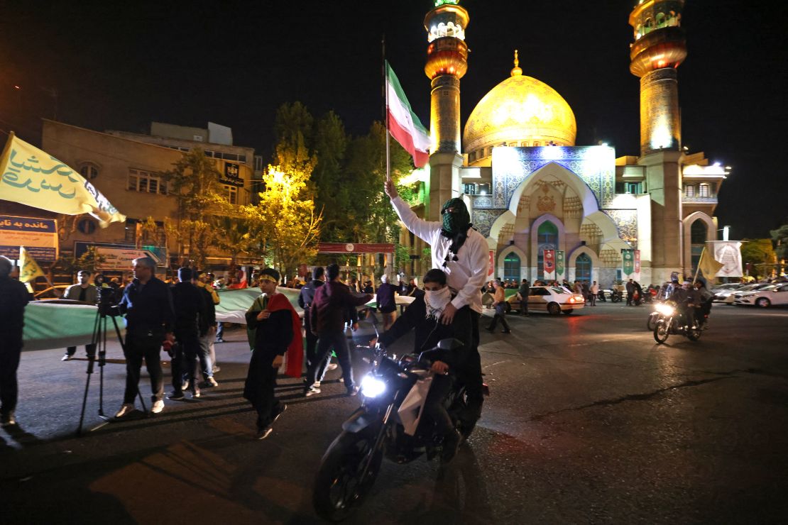 Demonstrators wave Iran's flag as they gather at Palestine Square in Tehran on April 14, 2024, after Iran launched a drone and missile attack on Israel.